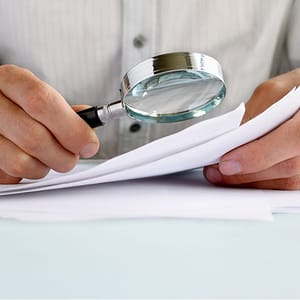 Man using a magnifying glass to read a document