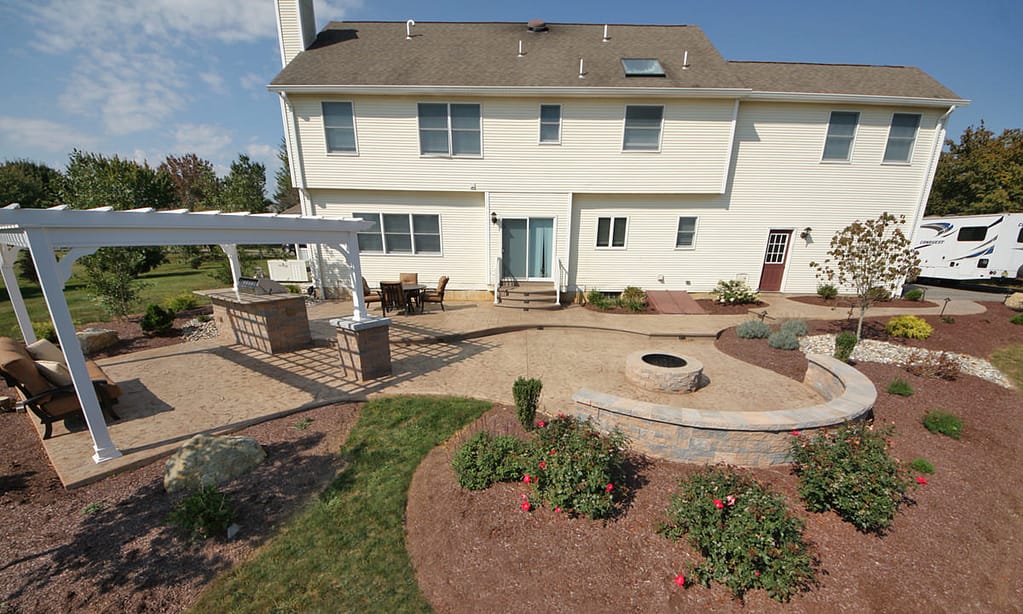 Multi-level stamped concrete patio with pergola and fire pit in Lehigh Valley backyard