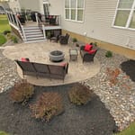 A decorative stamped concrete patio surrounded by a mulch and river stone landscape bed.