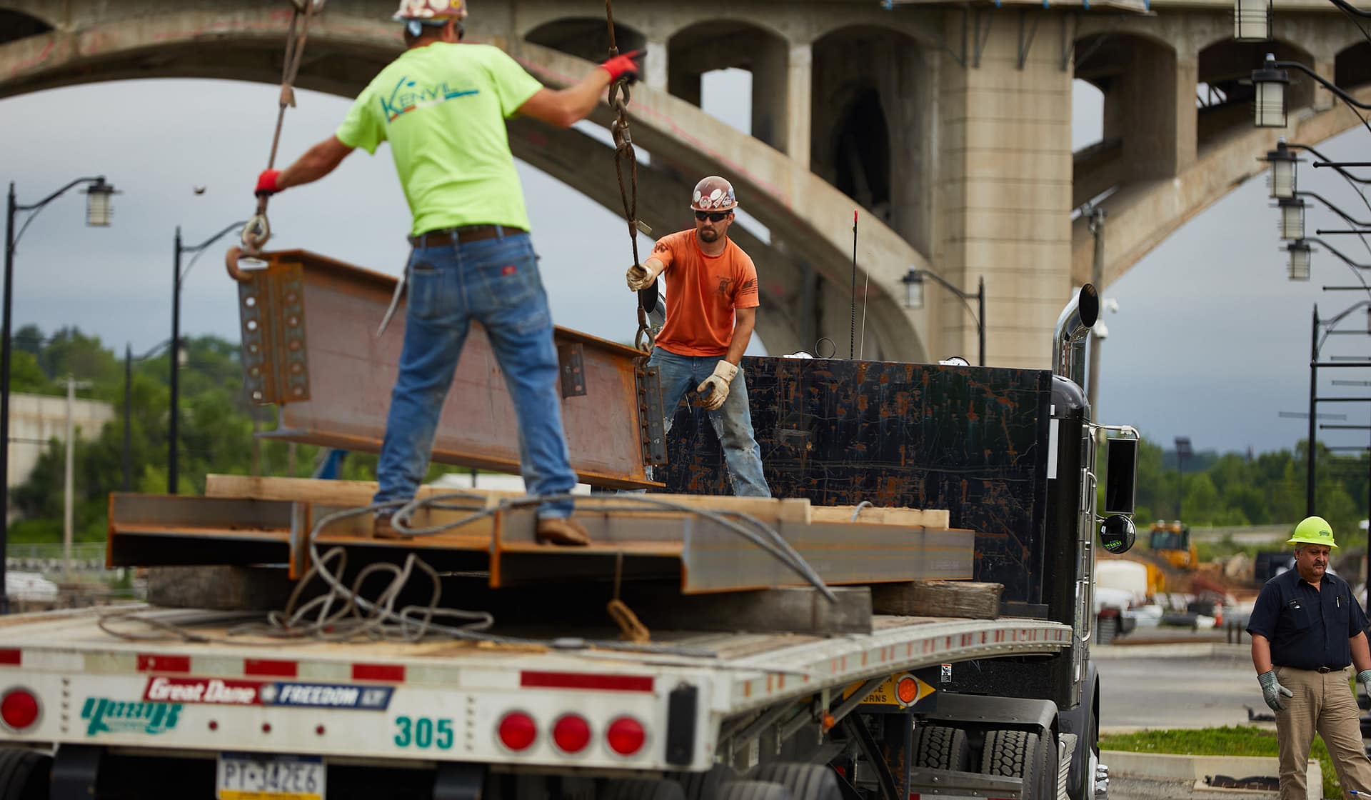 Workers unloading steel beams from a flatbed truck at the 615 Waterfront site in Allentown