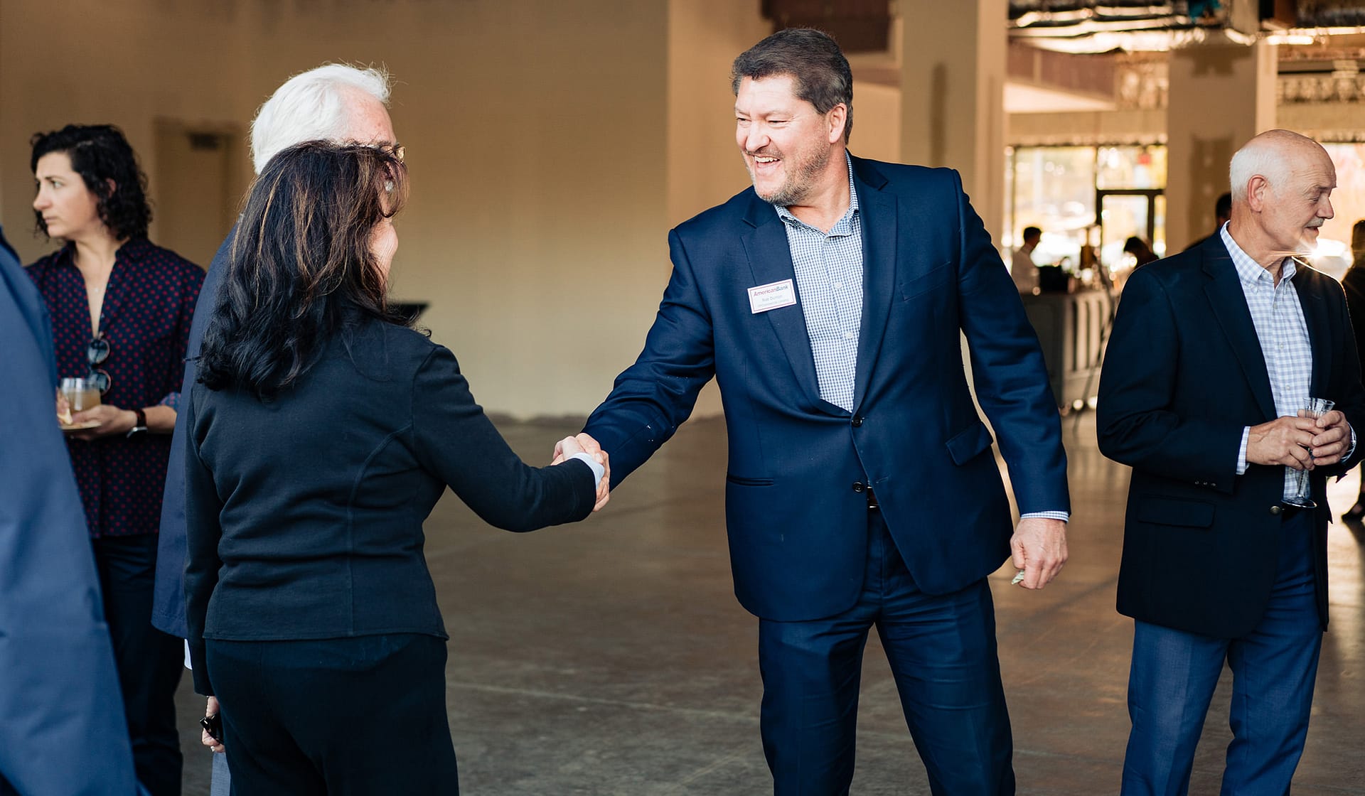 Two guests shaking hands at the 615 Waterfront grand opening celebration