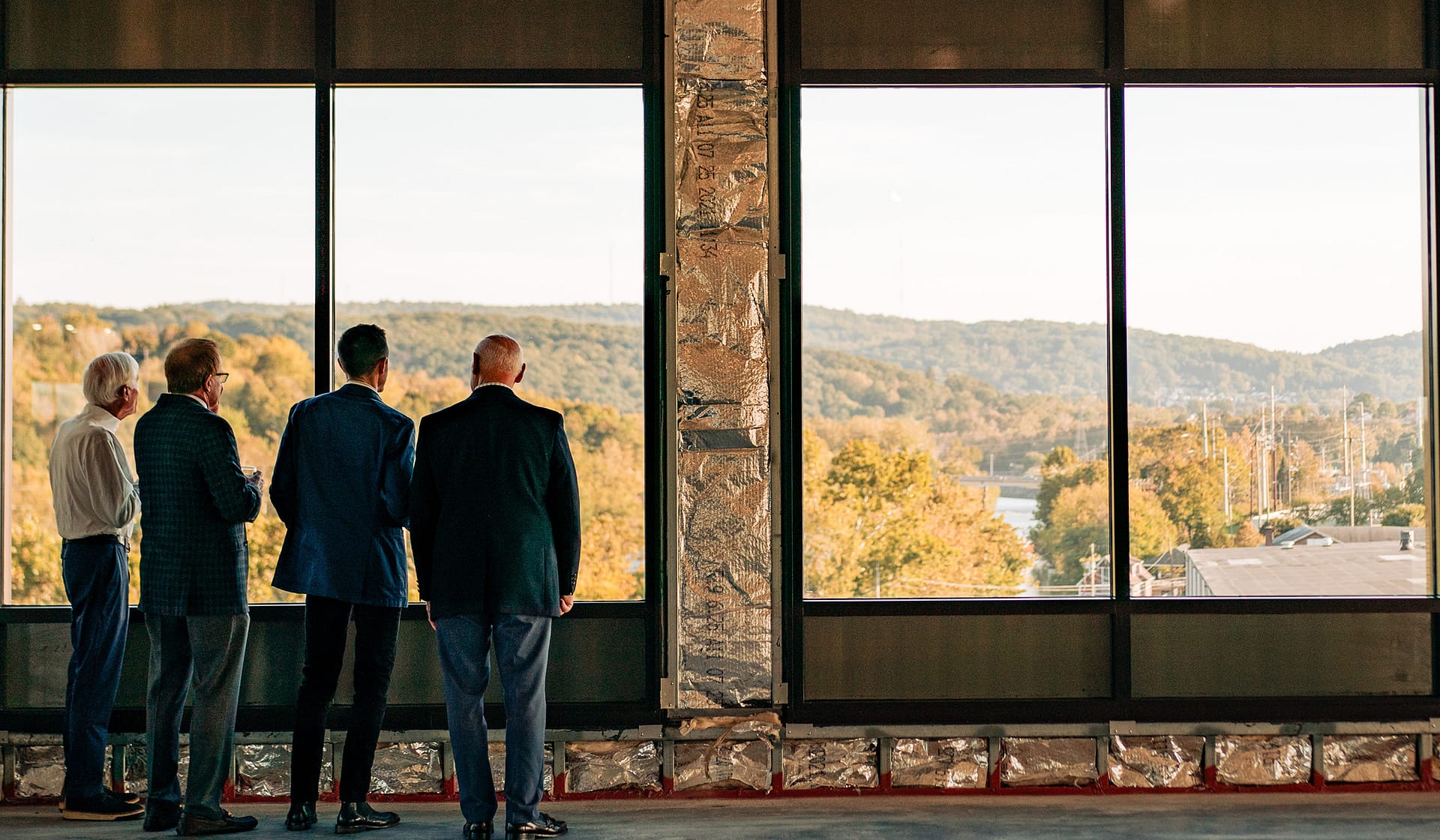Guests gathered at floor-to-ceiling windows overlooking the Lehigh River at an evening event