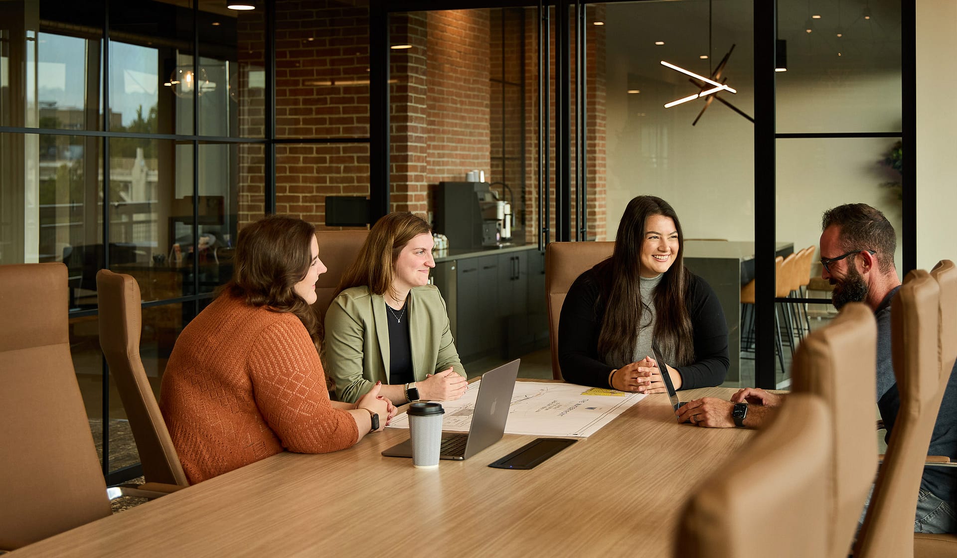 Colleagues collaborating over laptops in a brick-walled 615 Waterfront meeting room