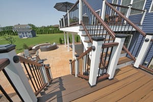 Elevated deck with stairs leading to a stamped concrete patio and outdoor living space
